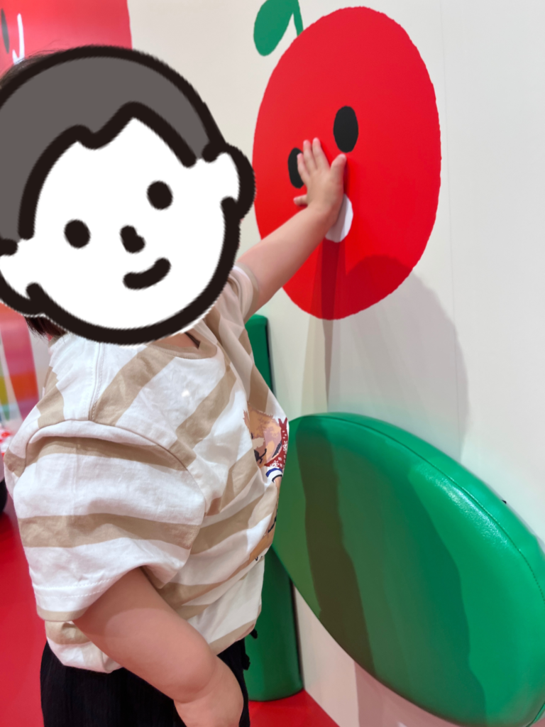 大きなりんごのすべり台のりんごのイラストを指差しする息子の様子の写真。