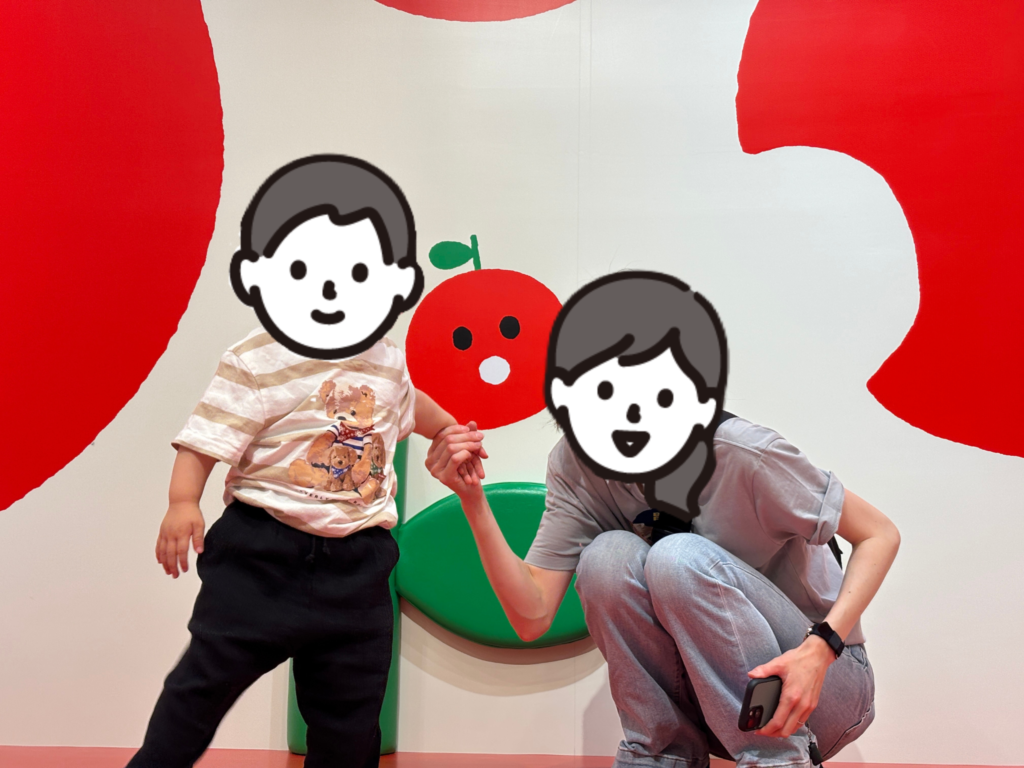 大きなりんごのすべり台の上の小さなリンゴのイラスト前で撮った記念写真。