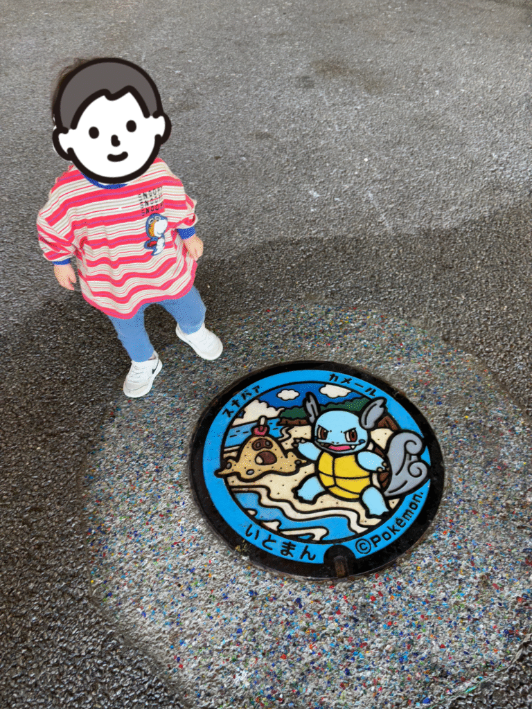 イベント広場にあったポケモンデザインのマンホールと息子の写真。